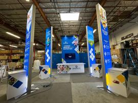 RENTAL: Modified RE-9138 Island Design with 16 ft. High Gravitee Storage Tower with Black Laminated Ceiling Soffits with Recessed Puck Lighting, Modified RE-1207 Large Rectangular Counter with Custom Size White Laminated Top, (4) Double-Sided Lightboxes a